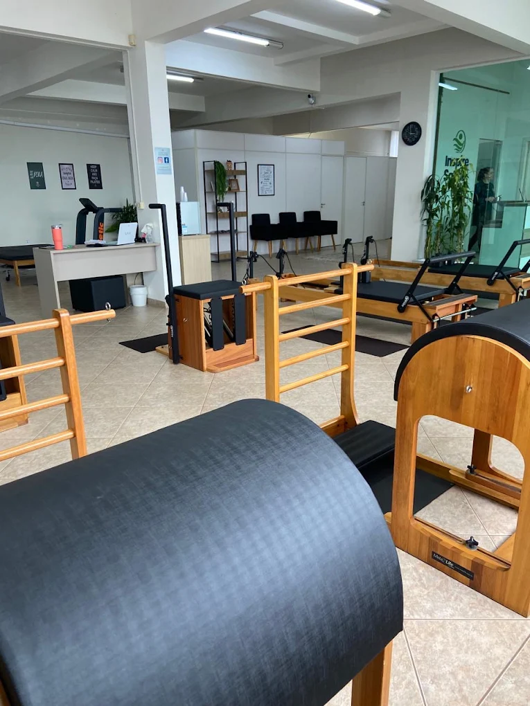 Aparelhos de Pilates em madeira e área interna da unidade Esplanada