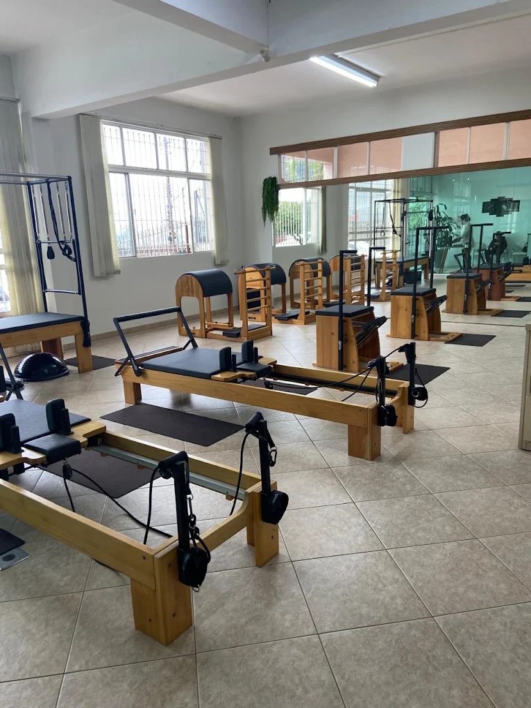 Sala de Pilates da unidade Esplanada com aparelhos de madeira, janelas amplas e parede de espelhos